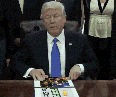 a man in a suit and tie is sitting at a table with a sign on it that says peep is king