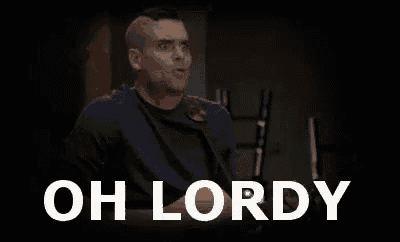 a man in a blue shirt is sitting in front of a black background with the words `` oh lordy '' written on it .