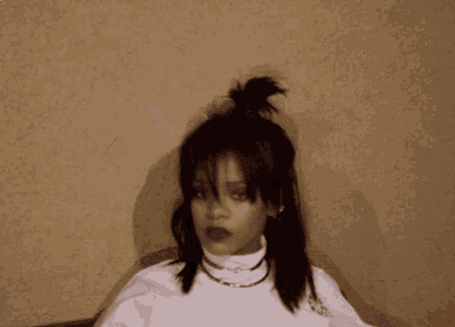 a woman with a bun in her hair is wearing a white turtleneck and a necklace .