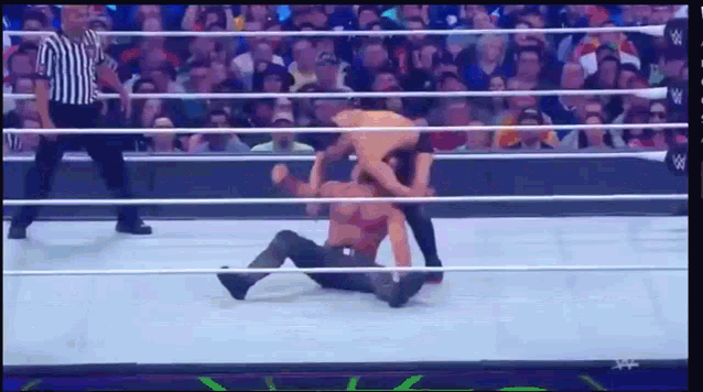 two men are wrestling in a wrestling ring with a referee watching
