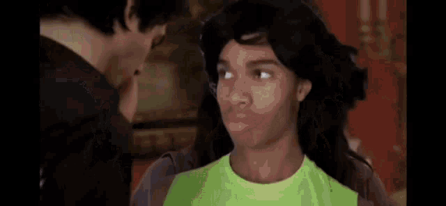 a man and a woman are kissing each other in a room . the woman is wearing a green shirt .