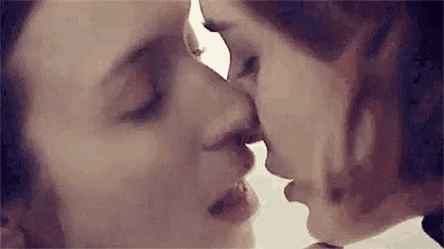 a man and a woman are kissing each other in a close up of their faces .