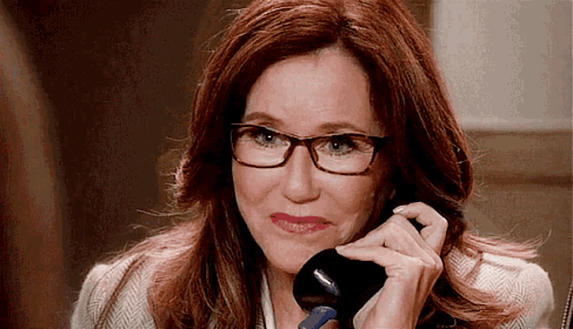 a woman with glasses is talking on a telephone