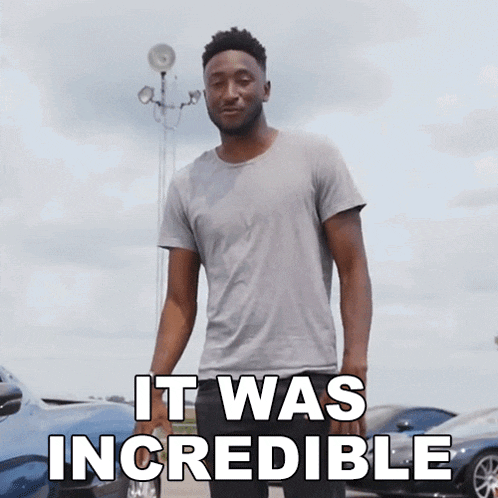 a man in a grey shirt says it was incredible in front of cars