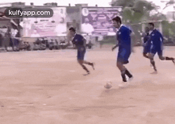 a group of boys are playing soccer on a dirt field .
