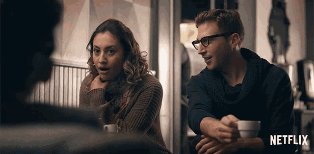 a man and a woman are sitting at a table with a netflix logo on the bottom