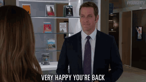 a man in a suit and tie says very happy you 're back to a woman