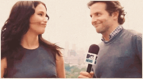 a man is holding a mtv news microphone while talking to a woman