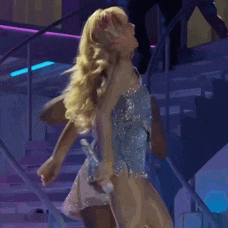 a blonde woman in a blue dress is dancing on stairs
