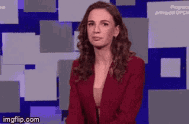 a woman in a red jacket is making a funny face and pointing at something .