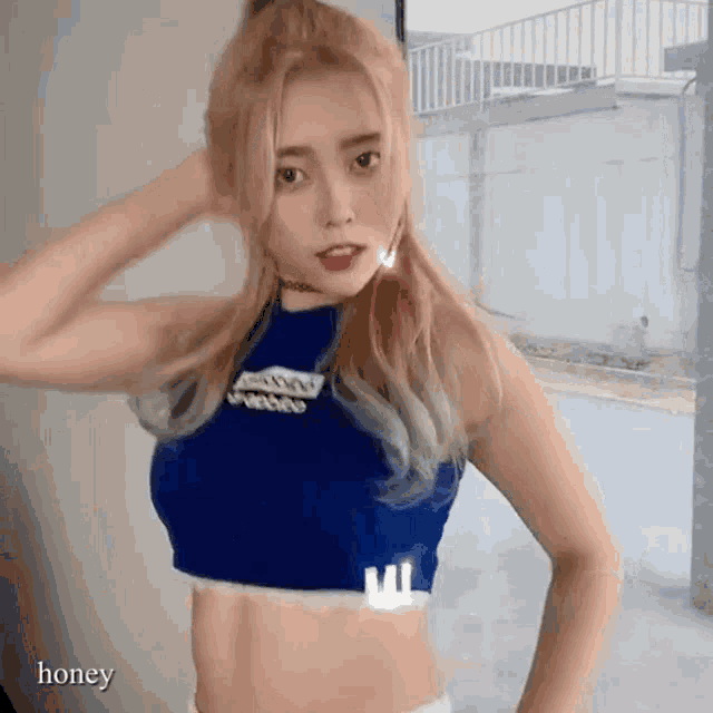 a woman in a blue crop top has the word honey written on her chest