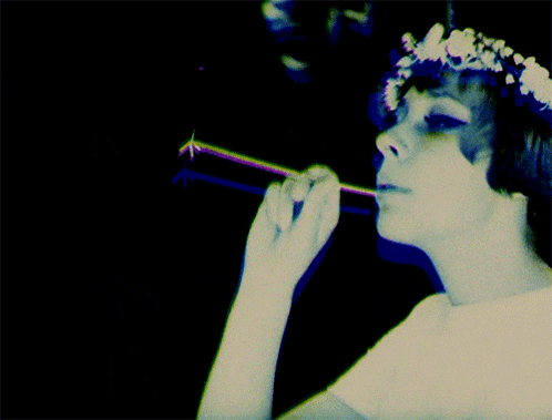 a woman with a flower crown on her head blowing a bubble