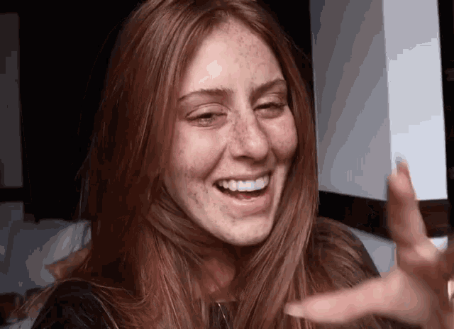 a woman with red hair and freckles is smiling
