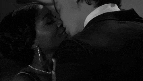 a black and white photo of a man kissing a woman