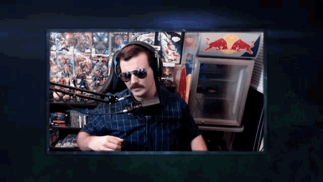 a man wearing sunglasses and headphones is sitting in front of a red bull cooler