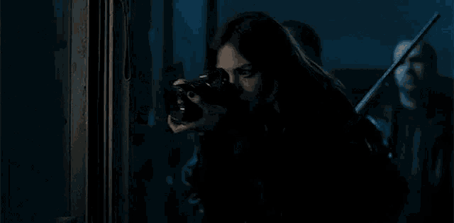 a woman is taking a picture of a man with a camera in the dark .