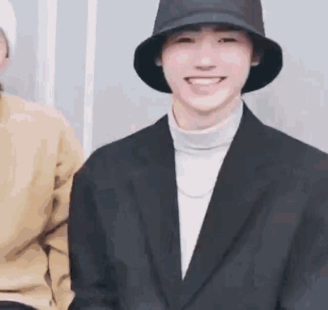 a man wearing a hat and a suit is smiling .