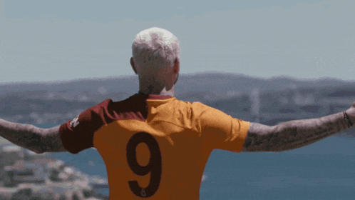 a man wearing a jersey with the number 9 on it stands with his arms outstretched