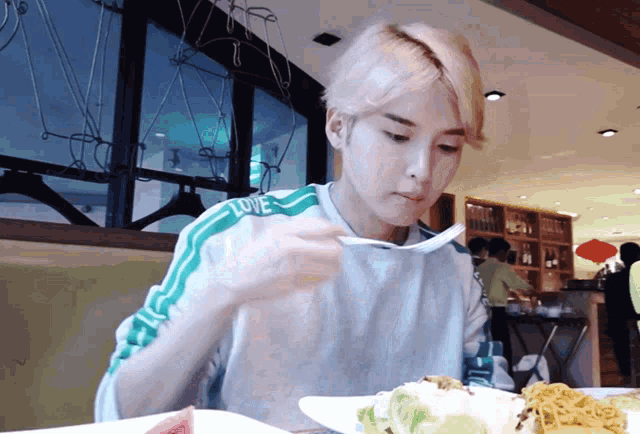 a person wearing a shirt that says love is eating noodles