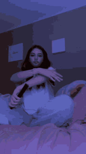 a girl sitting on a bed holding a microphone with a sign that says alone in the background