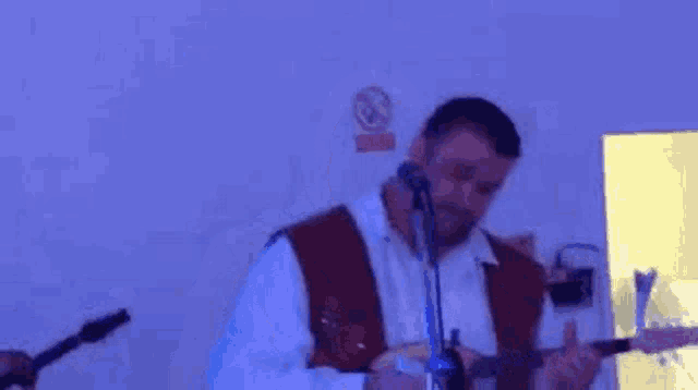 a man is playing a guitar and singing into a microphone while another man plays a guitar .