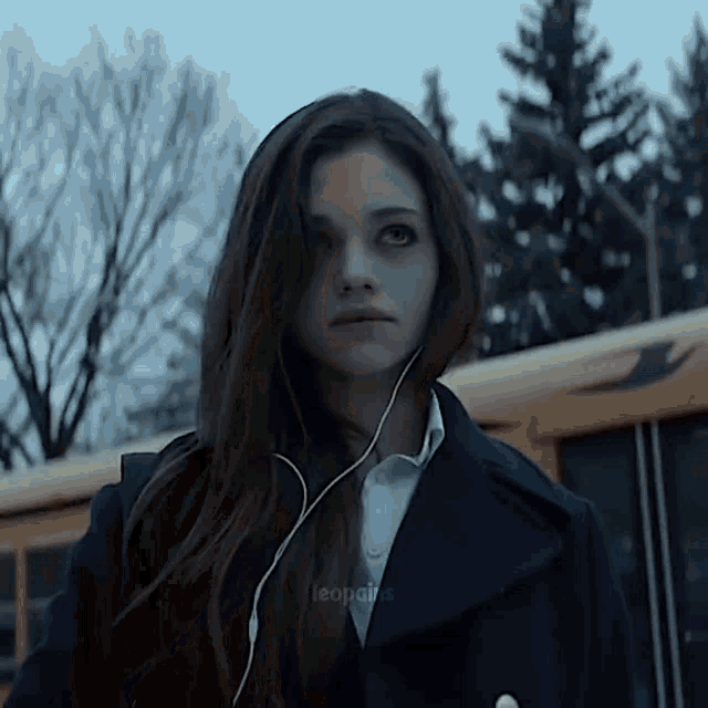 a girl wearing earbuds is standing in front of a school bus with the word leonairs on the bottom