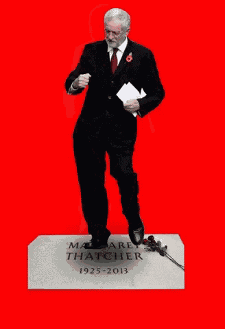 a man in a suit and tie is standing on a grave that says margaret thatcher 1925-2013