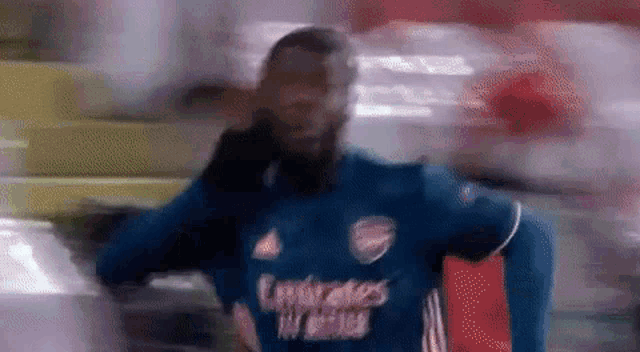 a blurry picture of a soccer player wearing a blue emirates fly emirates shirt .
