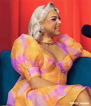 a woman in a colorful dress is sitting on a blue couch in front of a microphone .