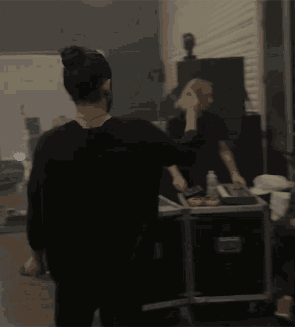 a man in a black shirt is standing in front of a mirror making a hand gesture