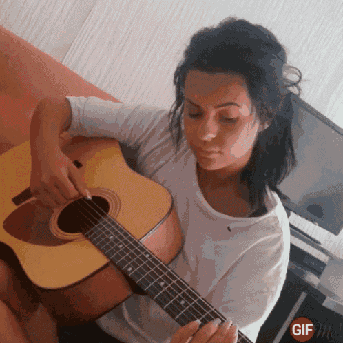 a woman playing an acoustic guitar with a gif me watermark