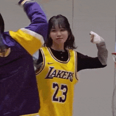 a girl wearing a lakers jersey is playing basketball with another girl .