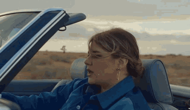 a woman in a blue jacket is sitting in a car