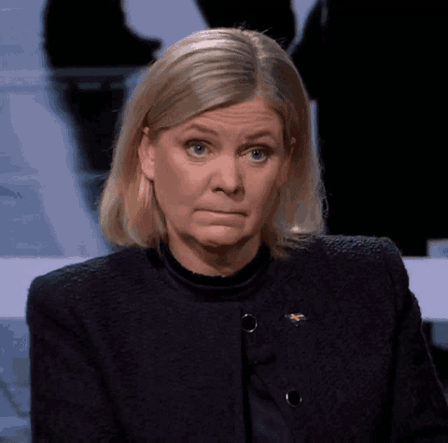 a woman wearing a black jacket has a yellow badge on her jacket that says ' sweden ' on it