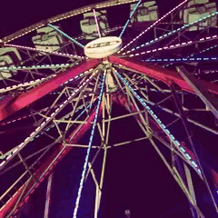 looking up at a ferris wheel at night with a white circle in the center