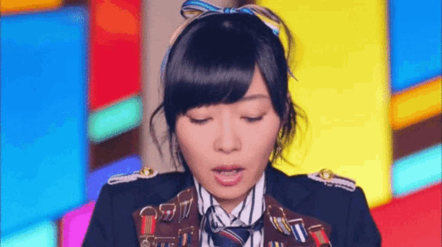 a woman in a military uniform and tie is standing in front of a colorful wall .