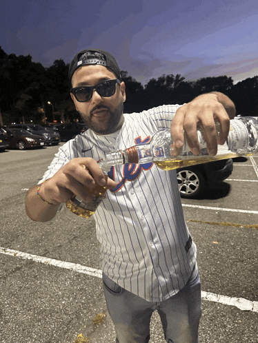 a man wearing a new york mets jersey is pouring a drink