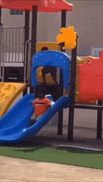 a child is riding a slide at a playground