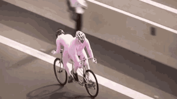 two people in pink outfits are riding a bike on a street