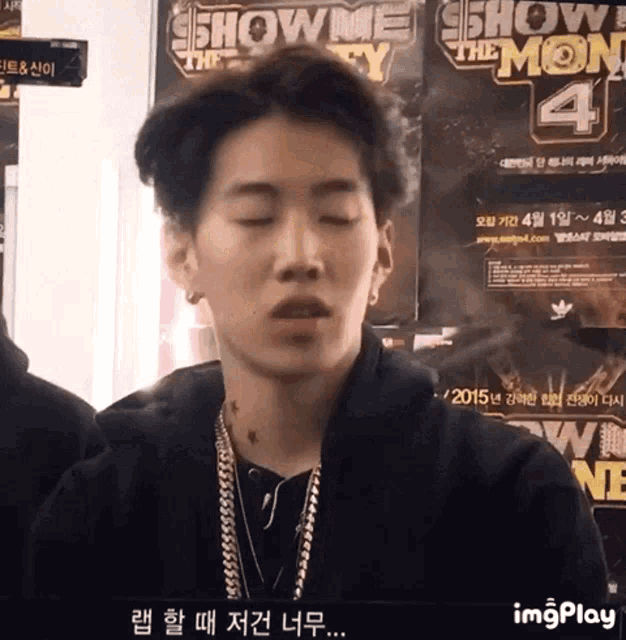 a young man is standing in front of a show me the money 4 poster