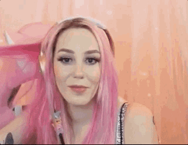 a woman with pink hair is wearing headphones and a bra .