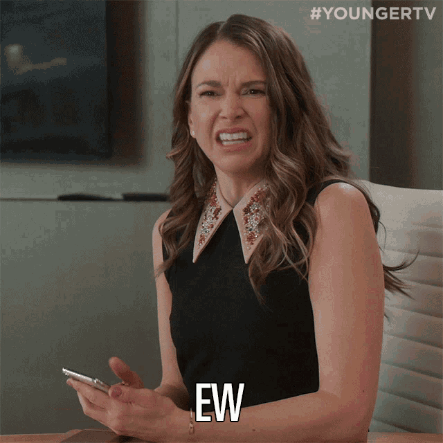 a woman sitting at a table with a cell phone and the word ew written on her face