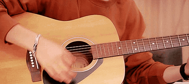 a person is playing an acoustic guitar with a bracelet around their wrist