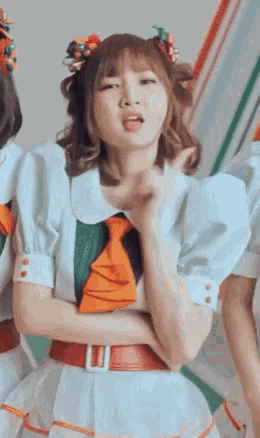 a girl in a white dress and tie is making a funny face while standing with her arms crossed .