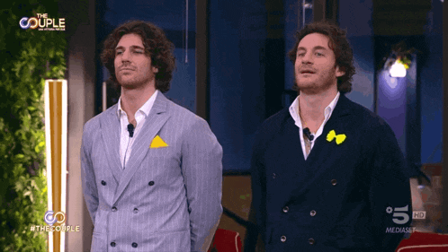 a couple of men standing next to each other on a tv show called the couple