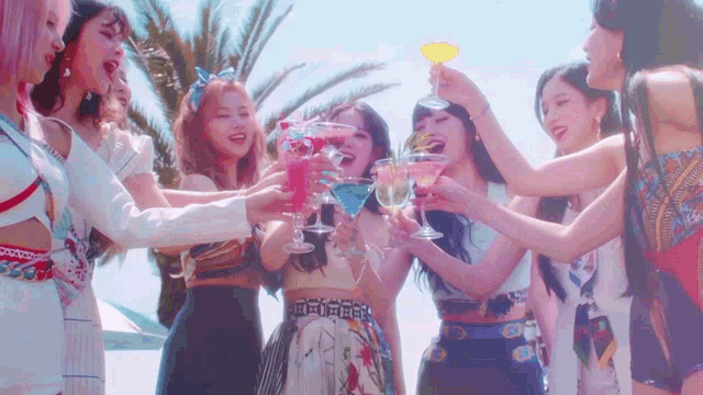 a group of young women are standing next to each other holding cocktail glasses .