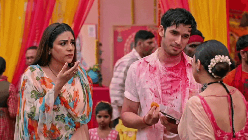 a man and a woman are standing next to each other in a crowd . the man is covered in colored powder .