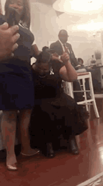 a woman in a blue dress is kneeling down in front of a man in a suit .