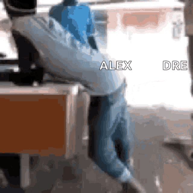 a man in a blue shirt is doing a handstand in front of a sign that says alex dre on it