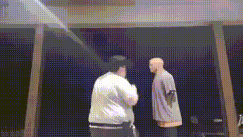 two men are standing next to each other in front of a black wall